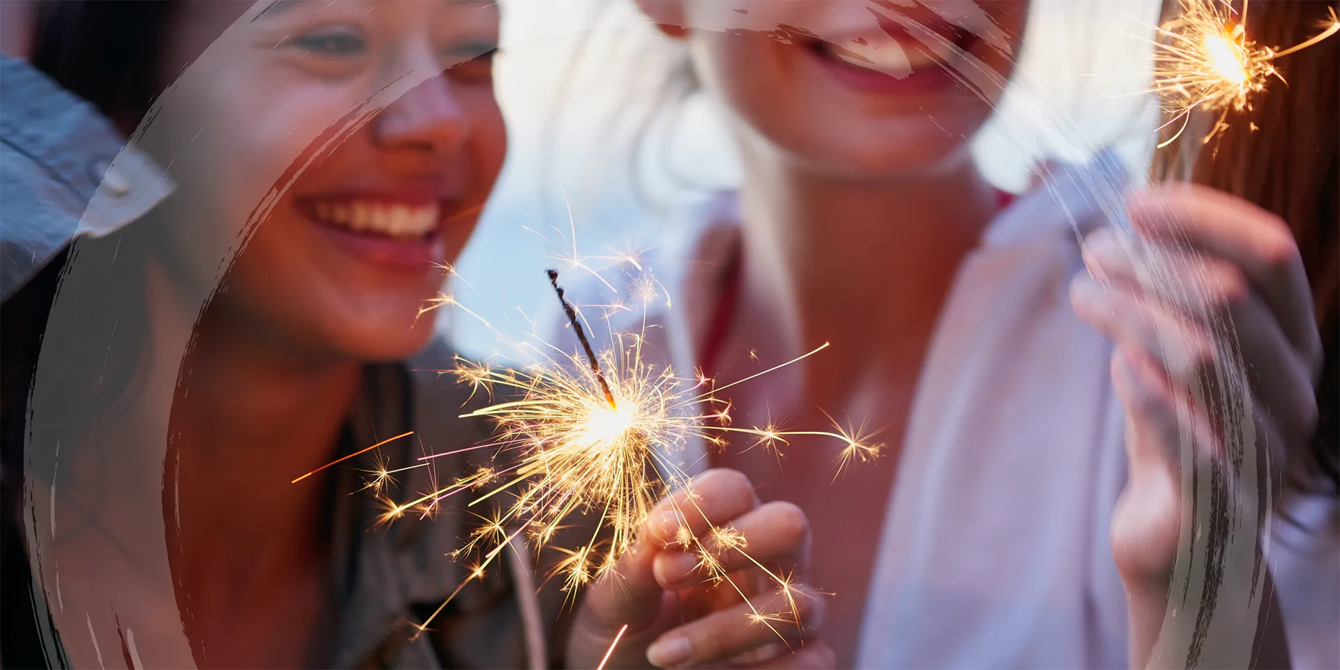 Photo of two people smiling, holding sparklers